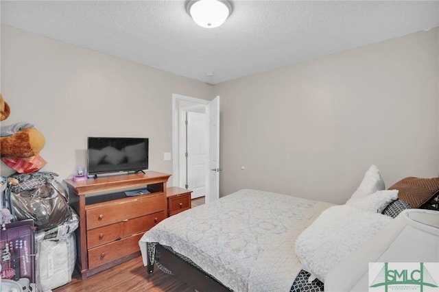 bedroom with a textured ceiling and light wood-type flooring