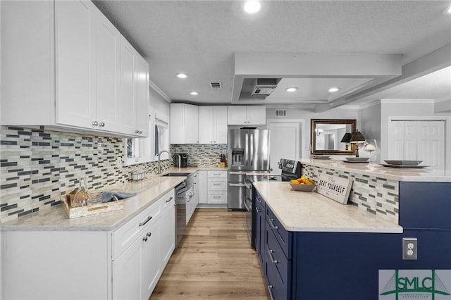 kitchen with light wood-type flooring, blue cabinetry, a sink, white cabinetry, and stainless steel appliances