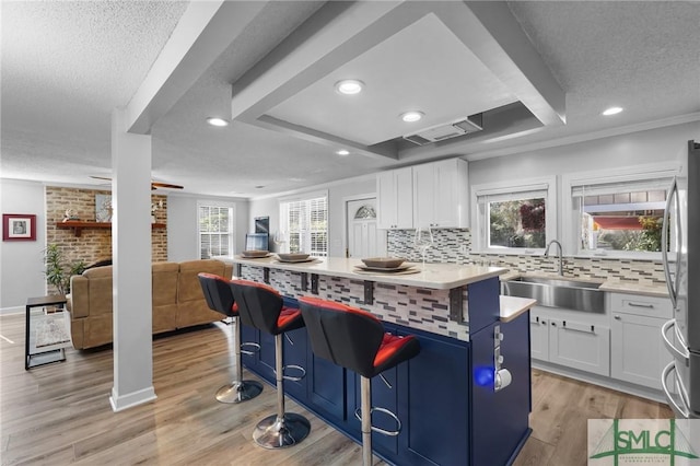 kitchen with a sink, light wood-style flooring, a kitchen bar, and white cabinets