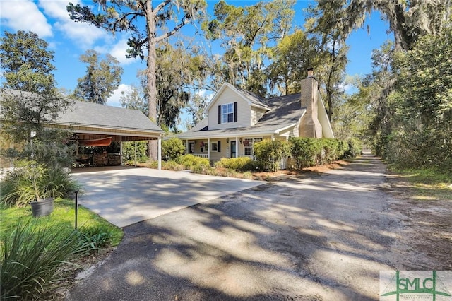 view of home's exterior with a chimney and driveway