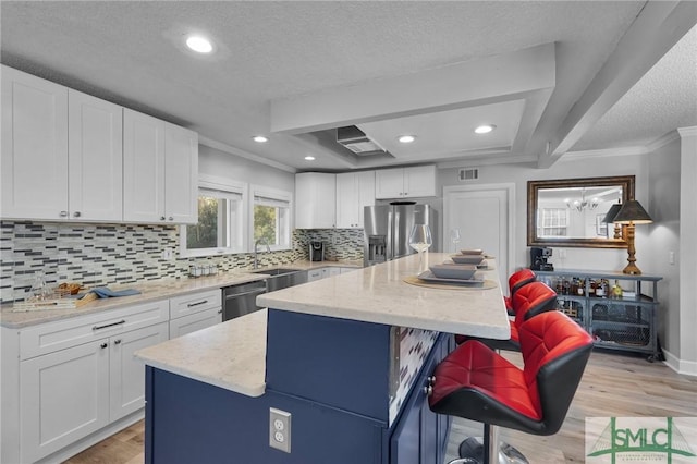 kitchen featuring white cabinetry, light wood-style floors, appliances with stainless steel finishes, a kitchen bar, and a center island