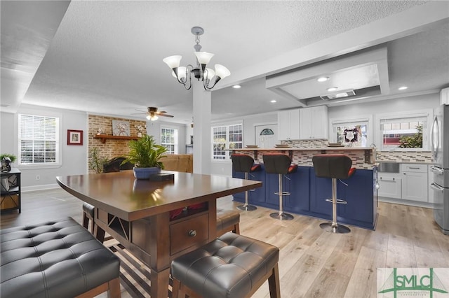 dining space with a brick fireplace, recessed lighting, a healthy amount of sunlight, and light wood-type flooring