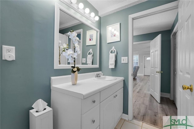 bathroom featuring vanity, baseboards, ensuite bathroom, and a textured ceiling