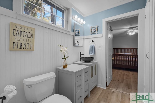 ensuite bathroom with toilet, wood finished floors, connected bathroom, and a sink