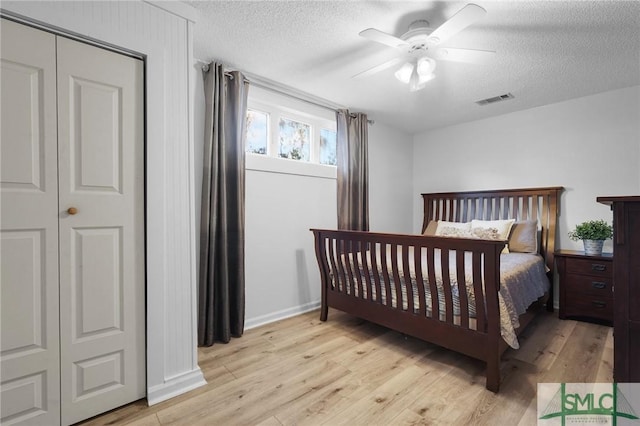 bedroom with ceiling fan, light wood-style floors, visible vents, and a textured ceiling