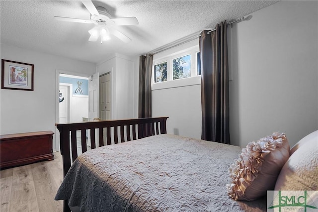 bedroom featuring a textured ceiling, light wood-type flooring, and ceiling fan