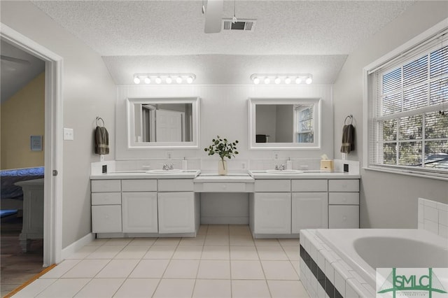 bathroom with visible vents, a sink, a textured ceiling, and two vanities