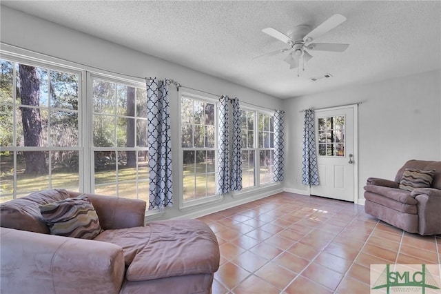 interior space with visible vents, a ceiling fan, a textured ceiling, tile patterned flooring, and baseboards