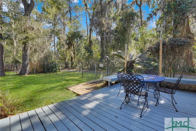 deck with outdoor dining area, a yard, and fence