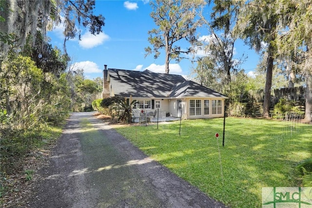 view of front facade featuring a front yard, fence, driveway, and a chimney