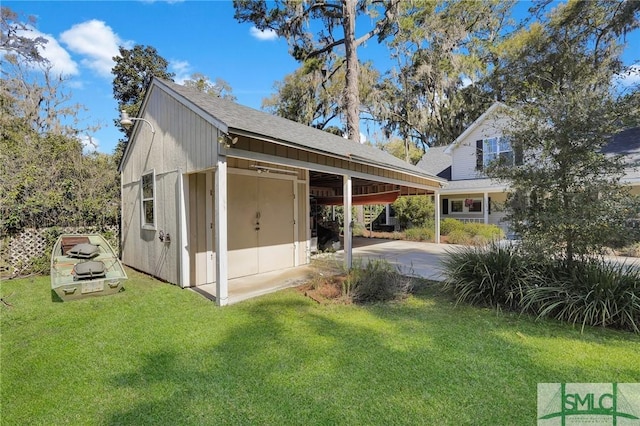 view of home's exterior with an outbuilding, driveway, a yard, roof with shingles, and an attached carport