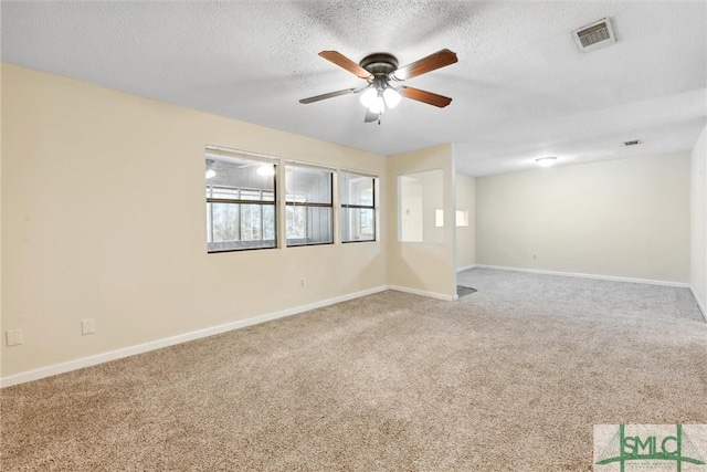 carpeted empty room with visible vents, baseboards, and a ceiling fan