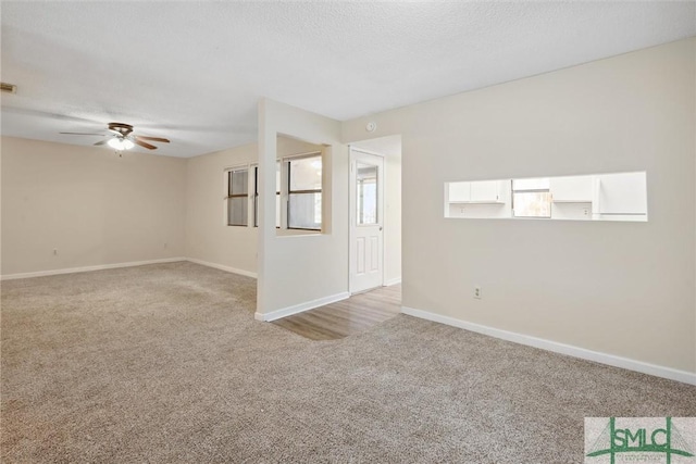 spare room featuring visible vents, light carpet, a textured ceiling, baseboards, and ceiling fan