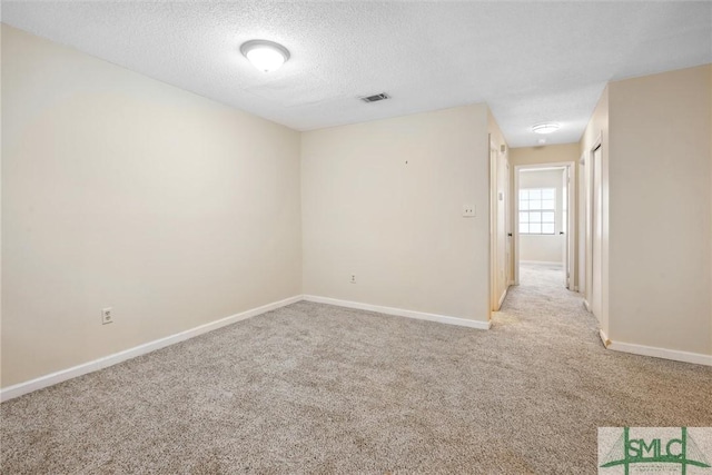 unfurnished room featuring a textured ceiling, visible vents, baseboards, and light carpet