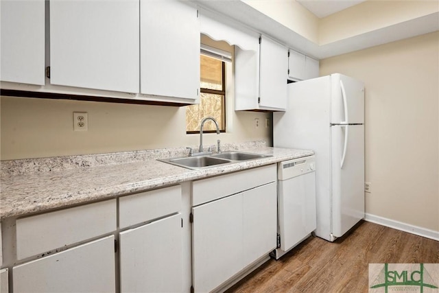 kitchen with light countertops, wood finished floors, white cabinets, white appliances, and a sink