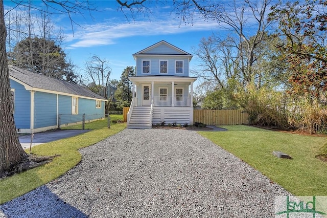 view of front of home featuring fence, stairs, a front yard, covered porch, and driveway