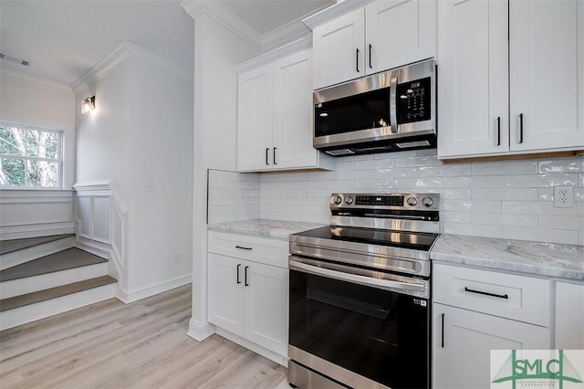 kitchen with light stone counters, decorative backsplash, appliances with stainless steel finishes, and ornamental molding