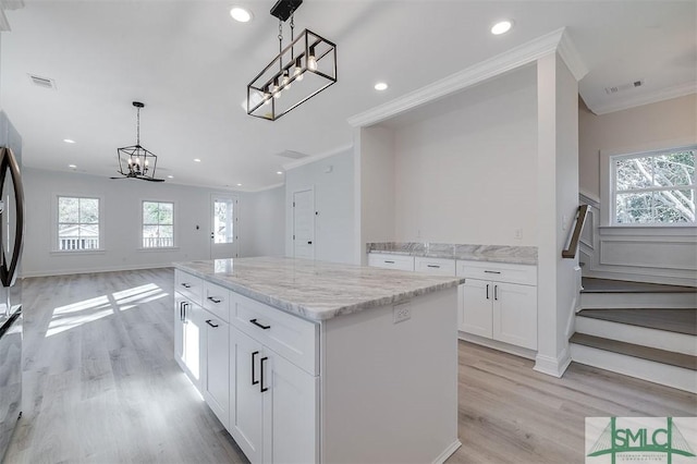 kitchen featuring a wealth of natural light, visible vents, open floor plan, and ornamental molding