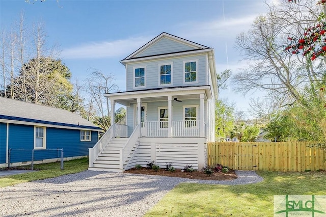 view of front of house with a porch, stairway, fence, and a front yard