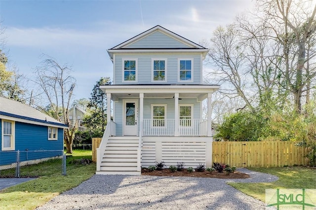 view of front of home with a front lawn, a porch, stairs, and fence