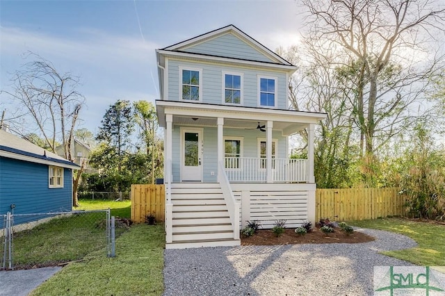 view of front facade with a porch, stairs, a front lawn, and fence