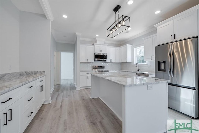 kitchen with a center island, crown molding, decorative backsplash, appliances with stainless steel finishes, and white cabinetry