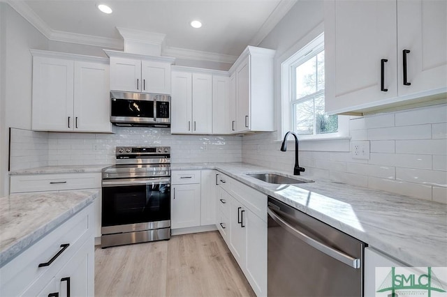 kitchen featuring a sink, stainless steel appliances, ornamental molding, and white cabinets