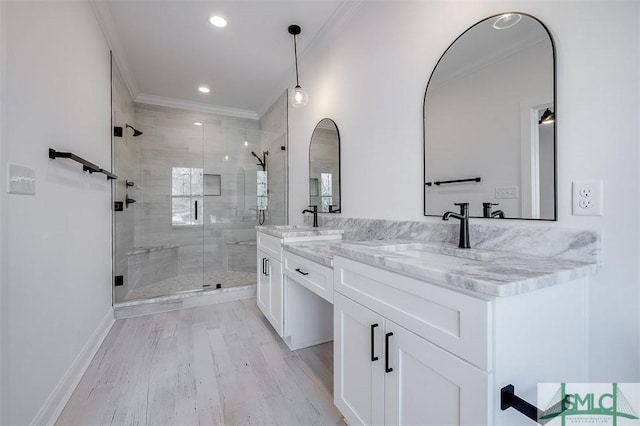 bathroom with a shower stall, ornamental molding, wood finished floors, and a sink