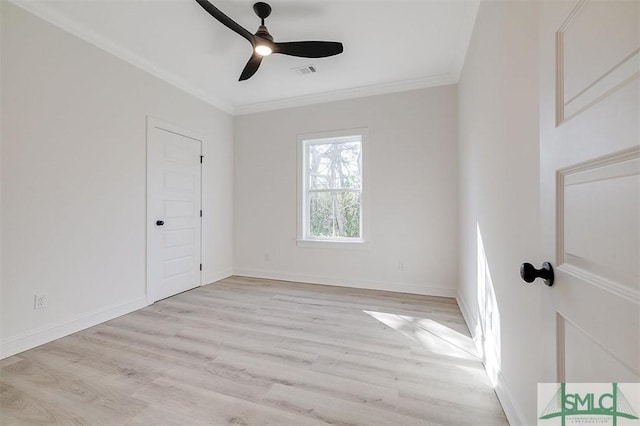 spare room featuring visible vents, ornamental molding, a ceiling fan, light wood finished floors, and baseboards