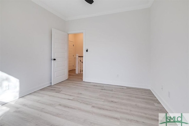 spare room featuring baseboards, crown molding, and light wood finished floors