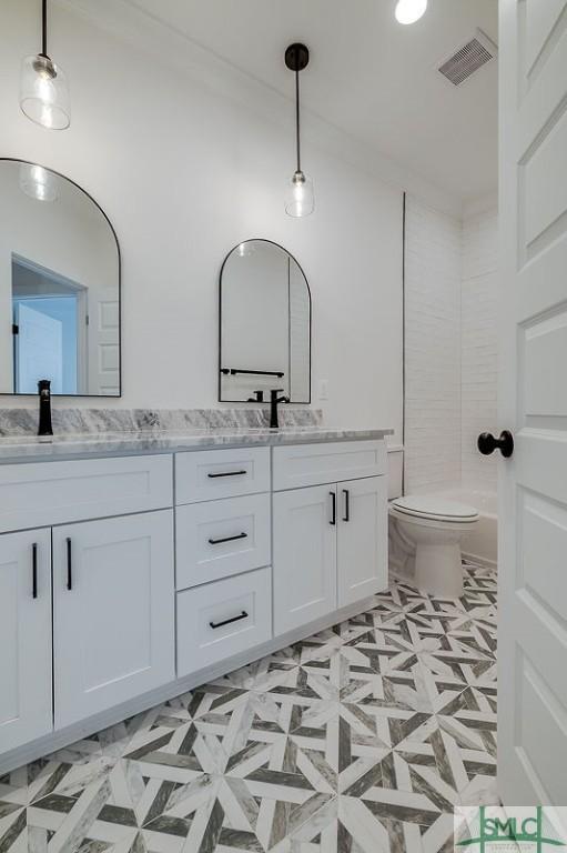 full bath with double vanity, visible vents, toilet, and a sink