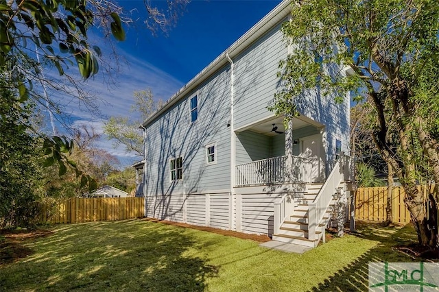 view of home's exterior with stairway, a yard, and fence