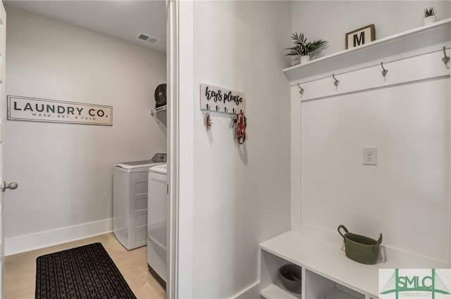 clothes washing area featuring visible vents, light wood-type flooring, washer and dryer, baseboards, and laundry area