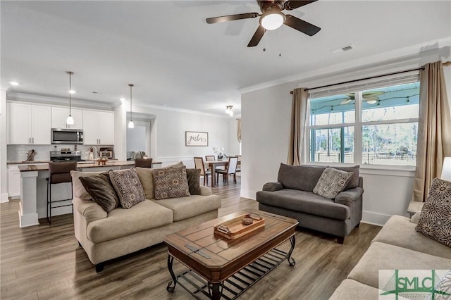 living room with a ceiling fan, visible vents, dark wood-style flooring, and ornamental molding