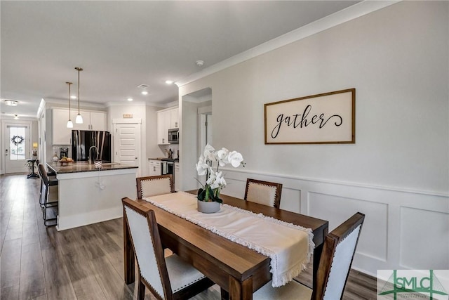 dining area with dark wood finished floors, recessed lighting, ornamental molding, wainscoting, and a decorative wall