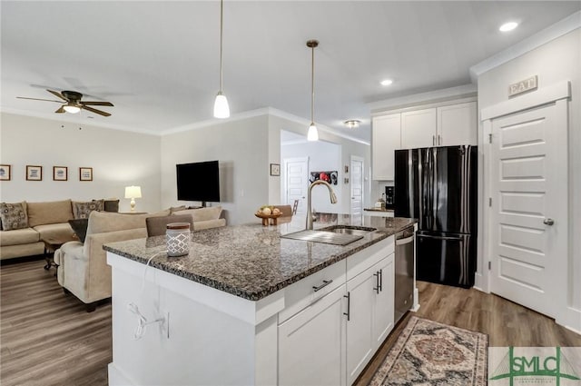 kitchen featuring dark stone counters, freestanding refrigerator, ornamental molding, a sink, and stainless steel dishwasher