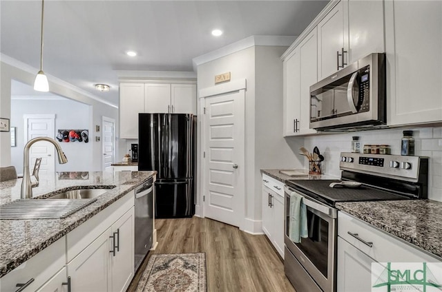 kitchen with backsplash, light wood-style flooring, white cabinets, stainless steel appliances, and a sink