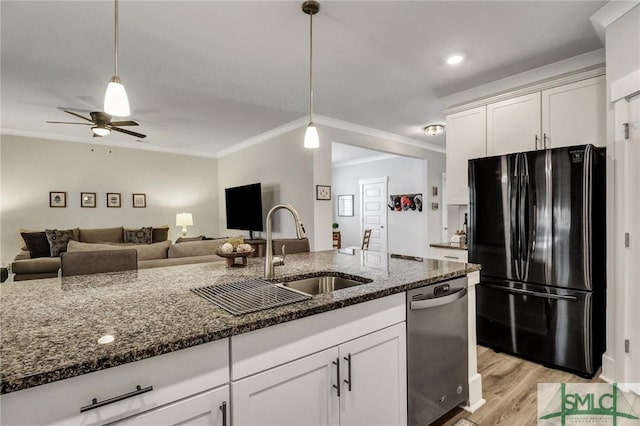 kitchen featuring dishwasher, dark stone countertops, freestanding refrigerator, and a sink