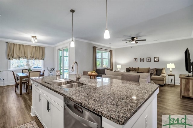 kitchen with a center island with sink, dark wood-style flooring, ornamental molding, a sink, and dishwasher