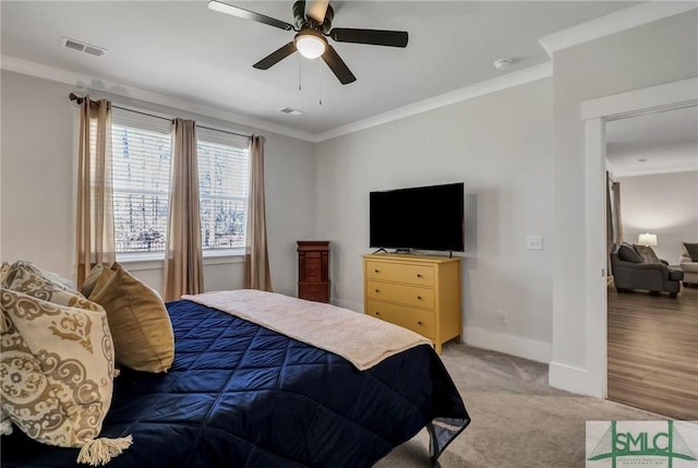 bedroom featuring visible vents, crown molding, baseboards, light colored carpet, and ceiling fan