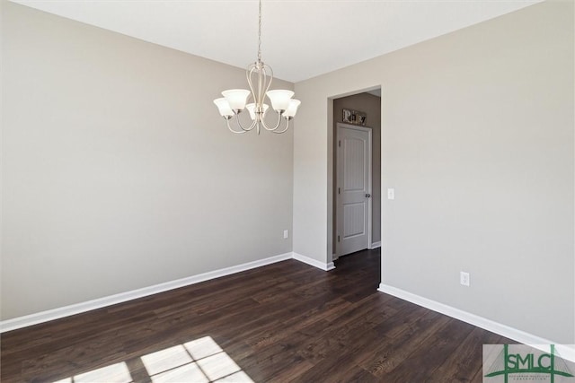 empty room featuring a chandelier, baseboards, and dark wood-style flooring