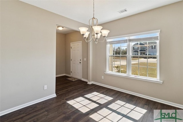 unfurnished dining area featuring visible vents, baseboards, a notable chandelier, and wood finished floors