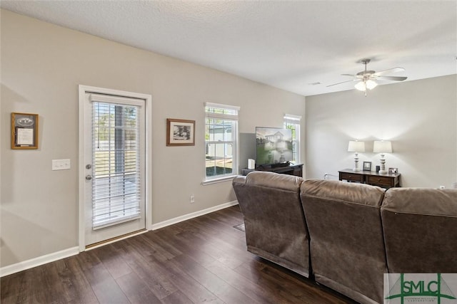 living area with baseboards, a ceiling fan, and dark wood-style flooring