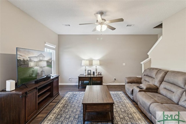 living area with visible vents, baseboards, dark wood-type flooring, and a ceiling fan