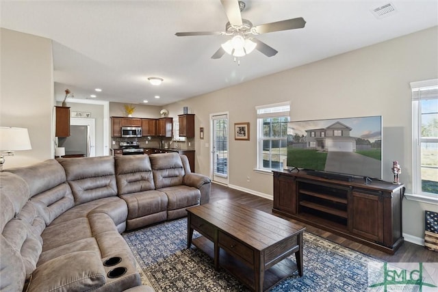 living room featuring ceiling fan, dark wood-style floors, visible vents, and baseboards