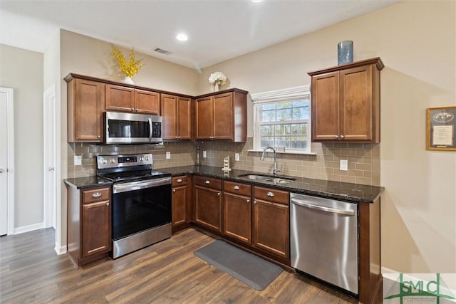 kitchen with visible vents, a sink, backsplash, appliances with stainless steel finishes, and dark wood-style flooring