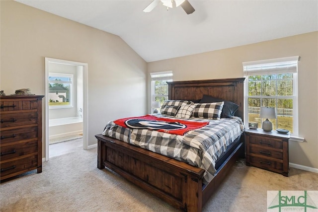 bedroom featuring a ceiling fan, ensuite bath, baseboards, light colored carpet, and vaulted ceiling