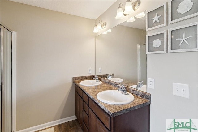 full bathroom featuring double vanity, wood finished floors, baseboards, and a sink