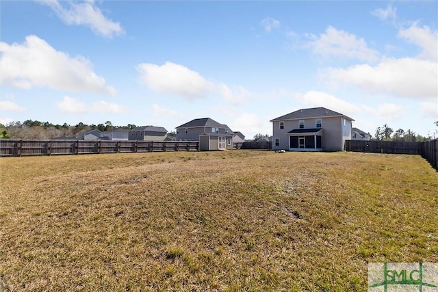 view of yard featuring a storage shed, a fenced backyard, and an outbuilding