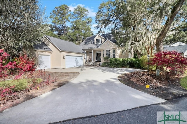 cape cod house with stucco siding, driveway, and an attached garage